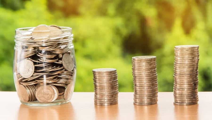 Stacks of coins next to a jar of coins.