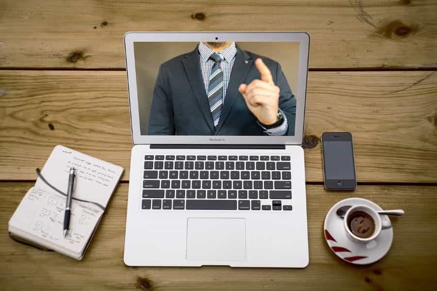 Someone watches an online course of a man in a suit speaking.