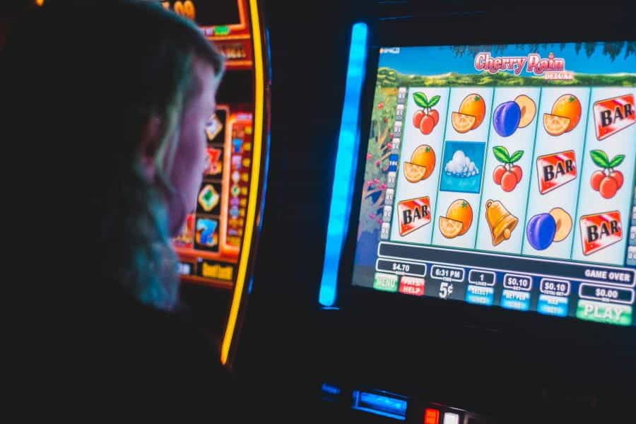 Person playing a brightly lit slot machine in a casino.