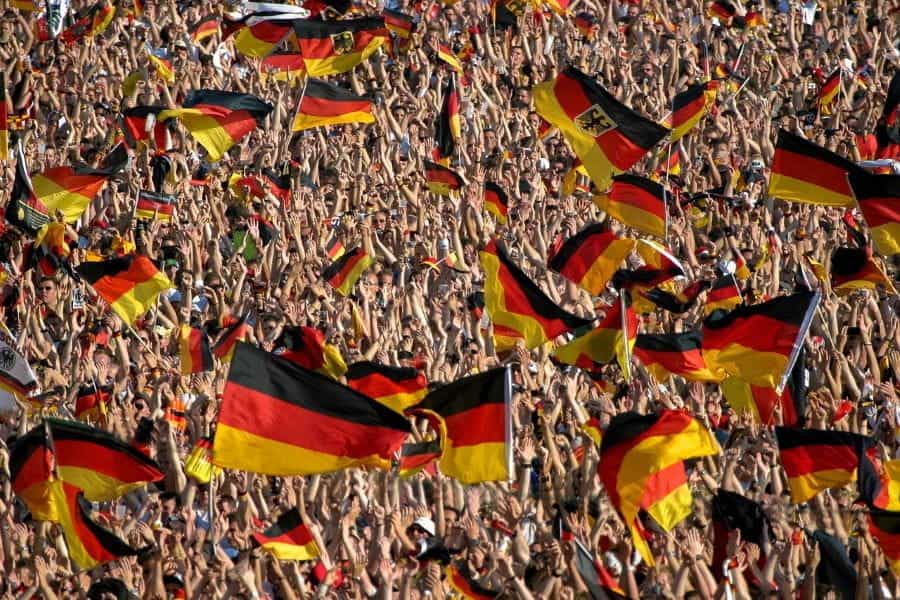 A crowd of football fans waving German flags.