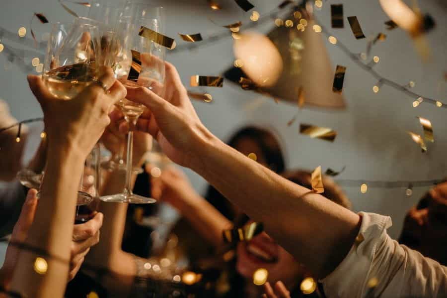 People toast champagne glasses, as gold confetti falls down.