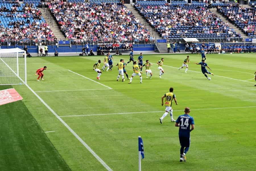 Footballers play on a pitch to a crowd of fans.