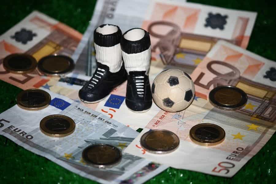 A pair of football boots standing on Euro notes and coins.