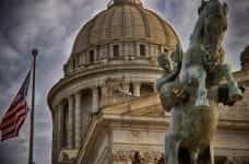 Oklahoma Capitol building with flag and horse statue.