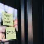 Two post-it notes are on a glass door, saying: Sorry, we are closed, and COVID-19.