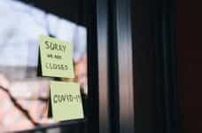Two post-it notes are on a glass door, saying: Sorry, we are closed, and COVID-19.