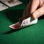 Two Ace cards lay face down with values revealed on poker table.
