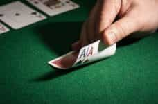 Two Ace cards lay face down with values revealed on poker table.