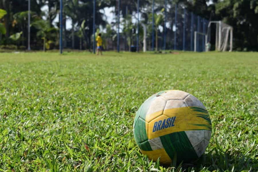 A soccer ball emblazoned with BRAZIL sits on an empty soccer field.