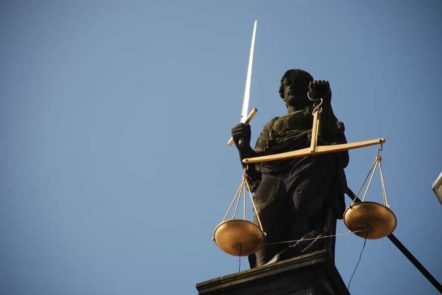 A statue of lady justice outside a courthouse. She is holding a sword and scales.