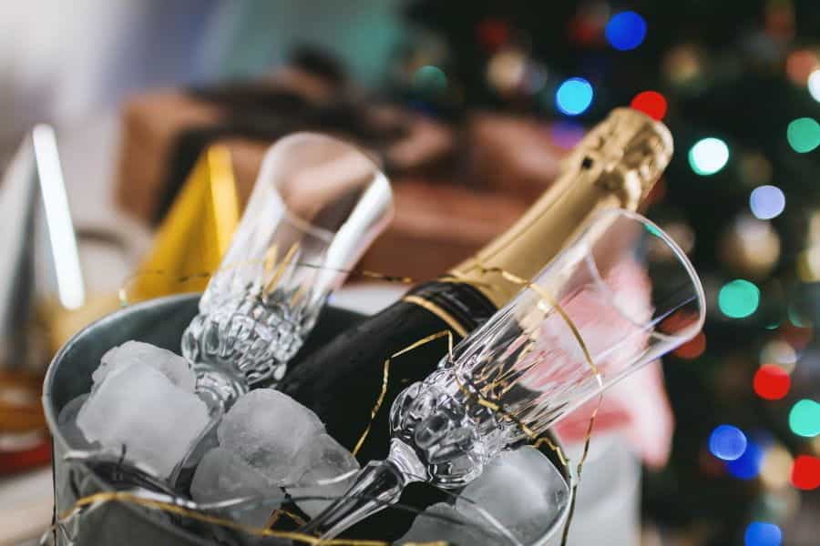 A bottle of champagne and glasses in a bucket of ice.
