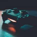 A black gaming controller with red light on a table.