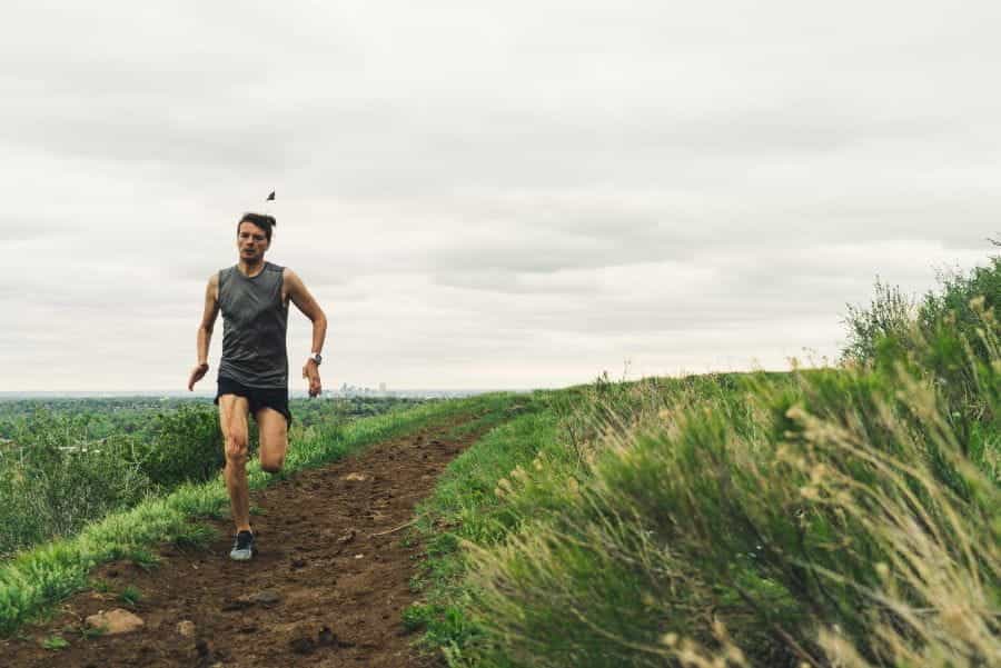 A runner runs down a muddy path next to grass.