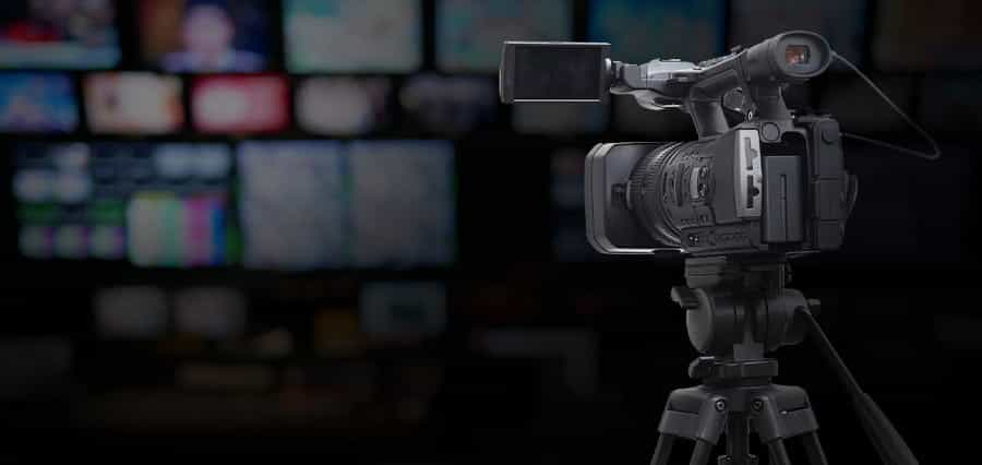 A TV camera with a blurred background of TV screens.