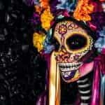 A woman wears an elaborate Día de Los Muertos costume.