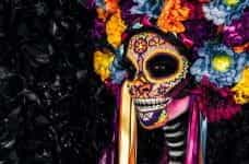 A woman wears an elaborate Día de Los Muertos costume.