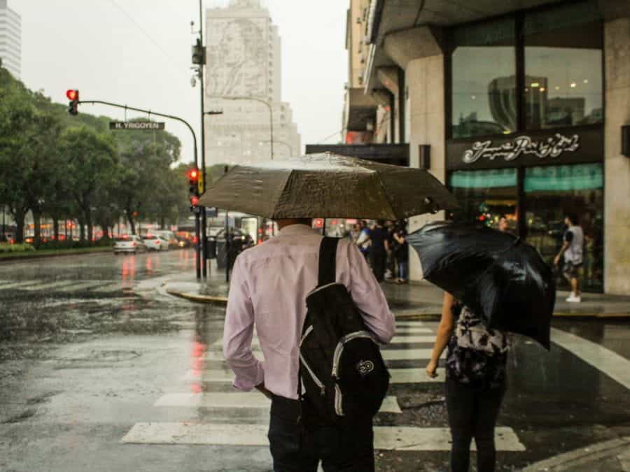 A couple holding an umbrella crosses the street on a rainy day in Buenos Aires, Argentina.