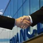 A deal is made with shaking hands in front of office.