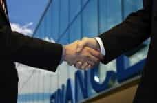 A deal is made with shaking hands in front of office.