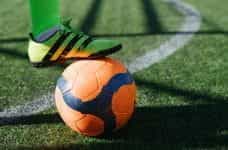 A footballer with foot on an orange football.