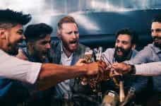Men toasting with bottles of beer.