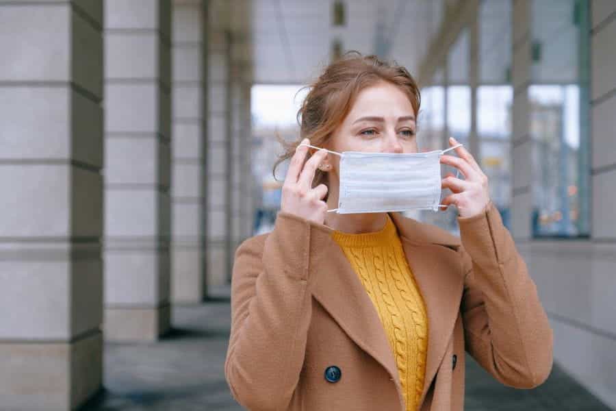 A white woman puts a medical mask over her face.