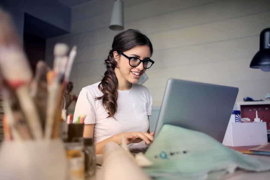 A woman sits at her desk, working on a laptop.