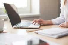 A woman uses a laptop on a desk.