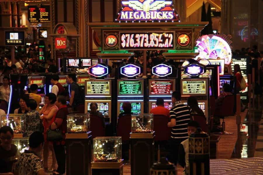 A brightly lit up row of slot machines in a Macau casino.