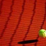 A tennis ball bouncing on a clay tennis court.