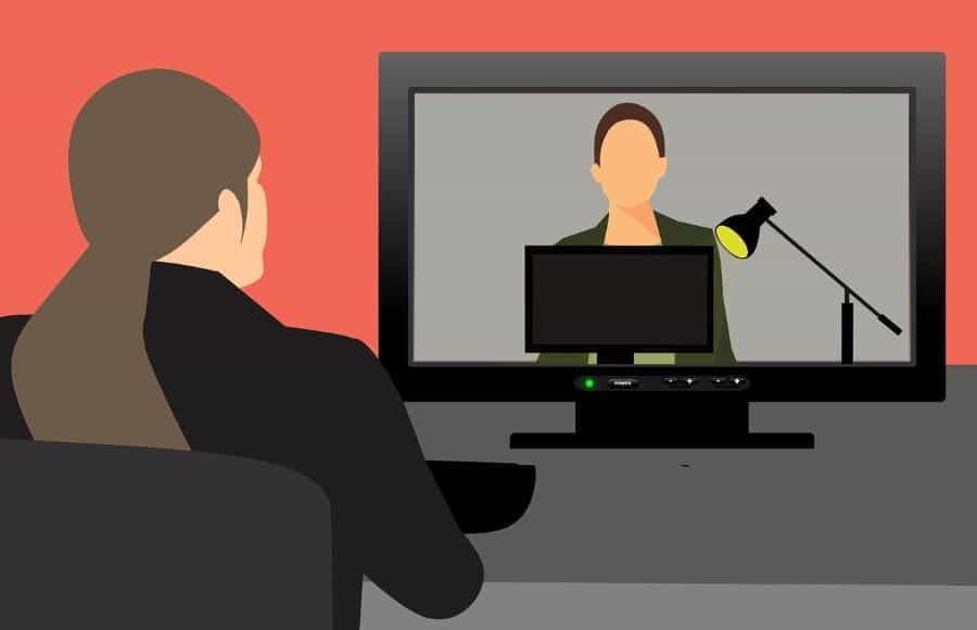 A woman in a suit watching a webinar.