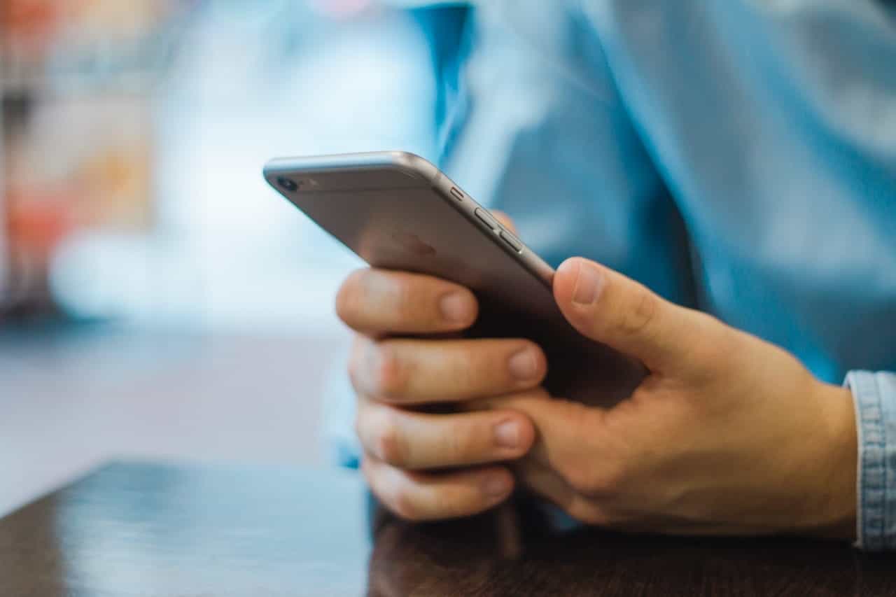 A person in a blue shirt holding a mobile phone.
