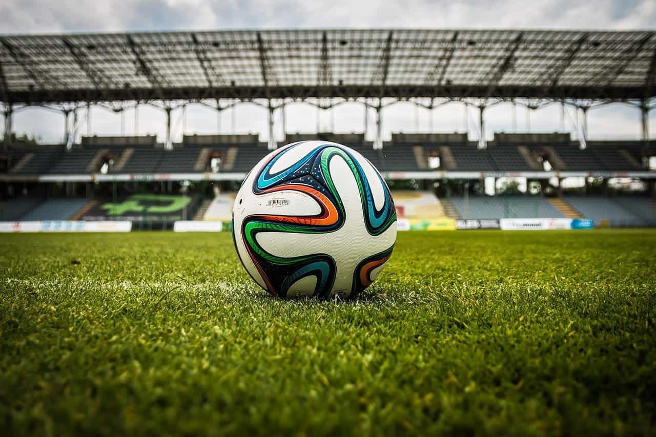 Sepak bola di lapangan di depan tribun kosong.