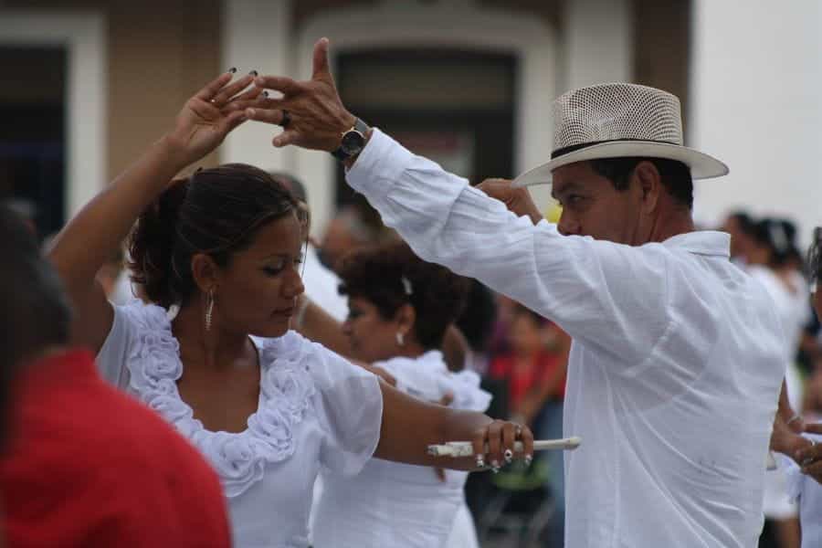 A man and a woman wearing white dance outside in Mexico.