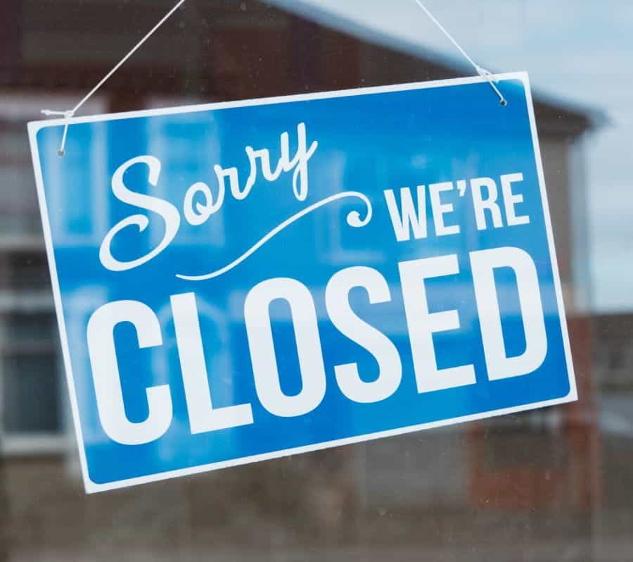 A blue sorry we're closed sign in a shop door.