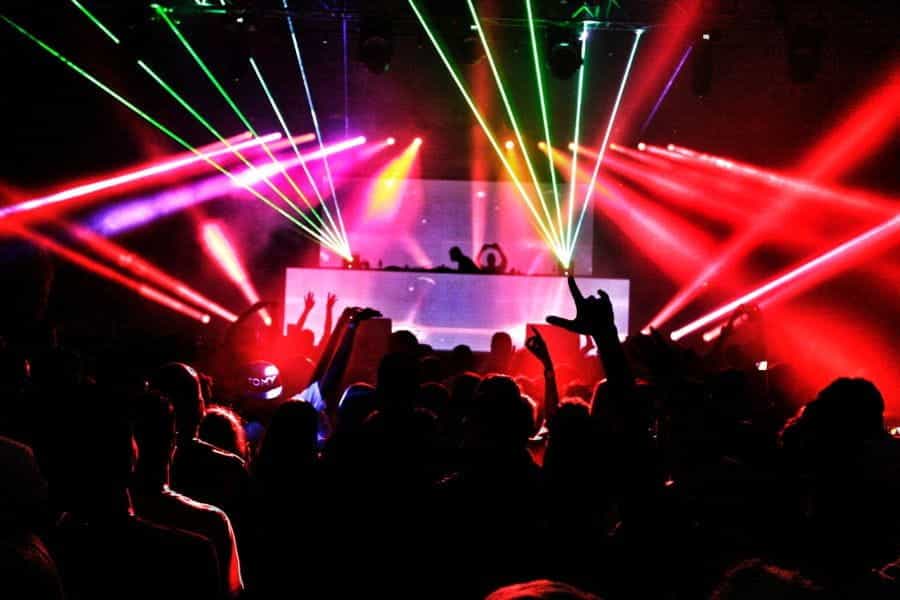 Kerumunan di klub malam dengan DJ dan lampu strobo.