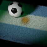 A soccer ball sits on grass emblazoned with the flag of Argentina.