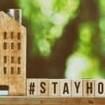Sebuah rumah kayu kecil berdiri di samping sejumlah balok kayu bertuliskan #StayHome.