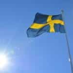 The Swedish national flag soaring high in the sky on a clear blue sunny day.
