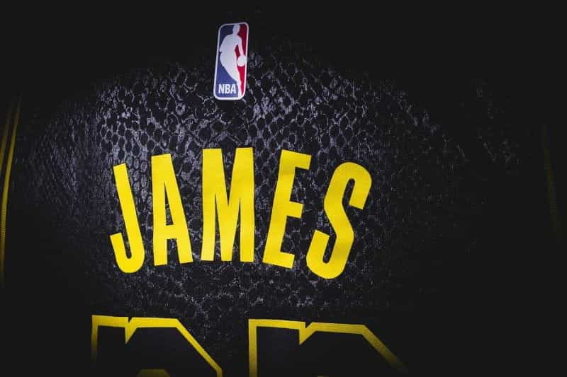 Seragam basket hitam bertuliskan JAMES dengan huruf kuning.