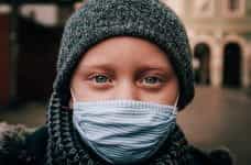 A child wearing a nose and mask covering during the coronavirus pandemic, staring into the camera.