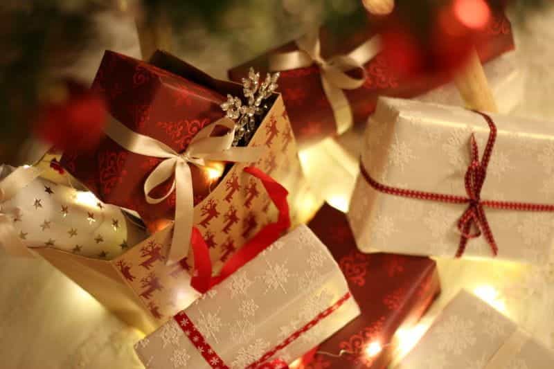 A pile of wrapped presents beneath a Christmas tree.