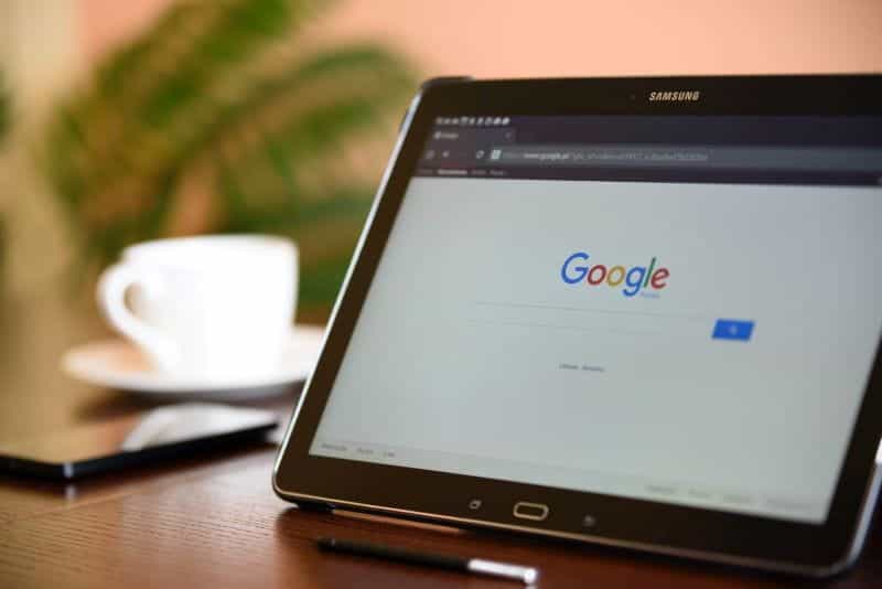 A tablet showing Google homepage and a coffee cup.