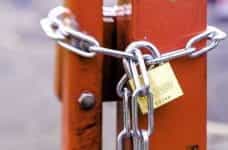 A locked gate or entrance, bound shut with a chain secured with a strong padlock.