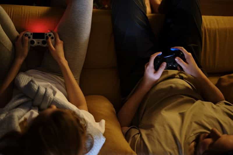Two people sitting on a sofa playing video games.