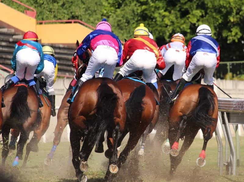 Colorful jockeys race horses around a track.