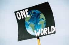 An environmental placard with planet earth painted on it and one world.