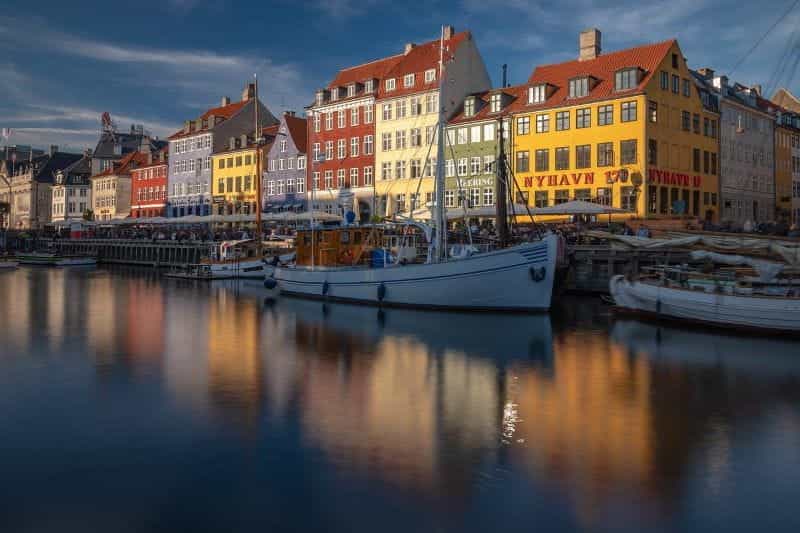 Distrik Nyhavn di ibu kota Denmark, Kopenhagen, dengan jalur pejalan kaki dan kapal yang berlabuh terlihat jelas.