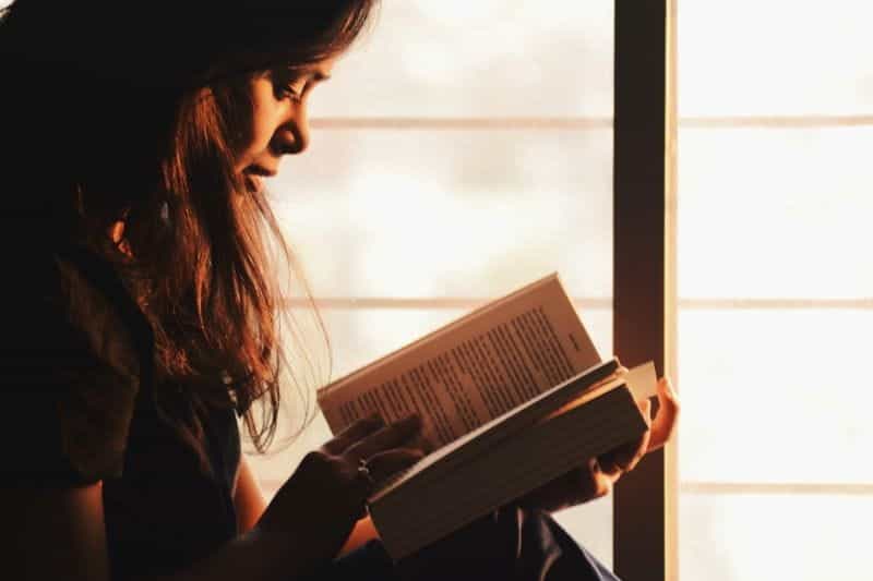 A woman sits reading a book.