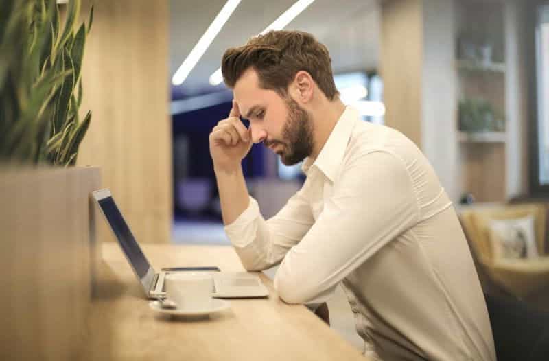 Seorang pria dengan secangkir kopi menggunakan laptop.